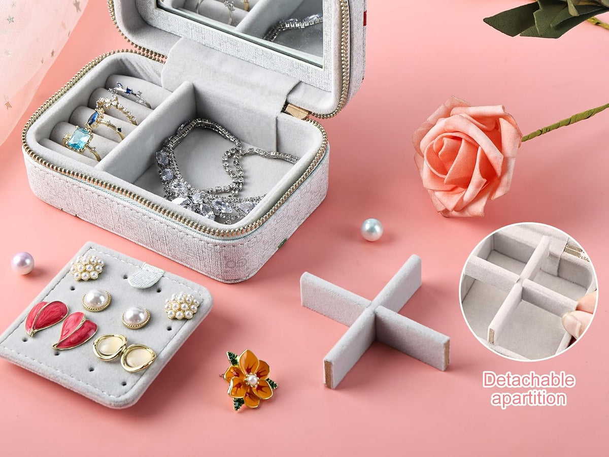 Gray jewelry box with detachable compartments on a pink background with flowers.