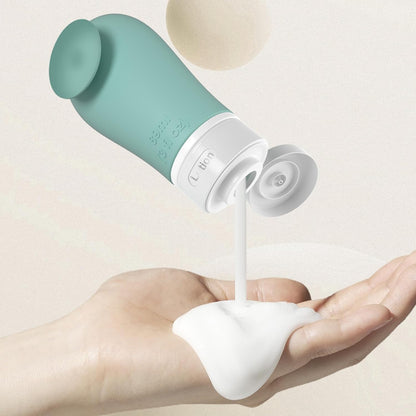 Green and white bottle dispensing liquid into a hand against a light background