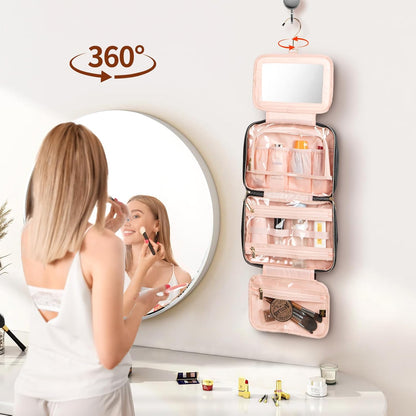 Woman applying makeup in front of a round mirror with a pink cosmetic bag hanging on the wall.